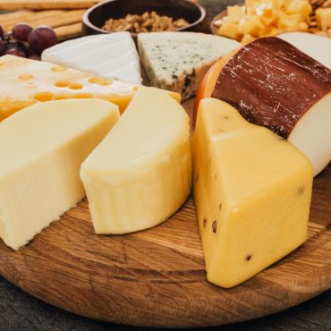 close up view of assortment of cheese on wooden cutting board